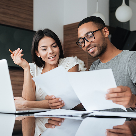 A young couple looking at paperwork and smiling