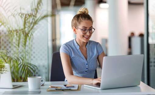 A young woman smiling and working on her laptop computer