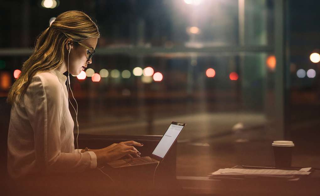 A young woman working on her laptop late at night