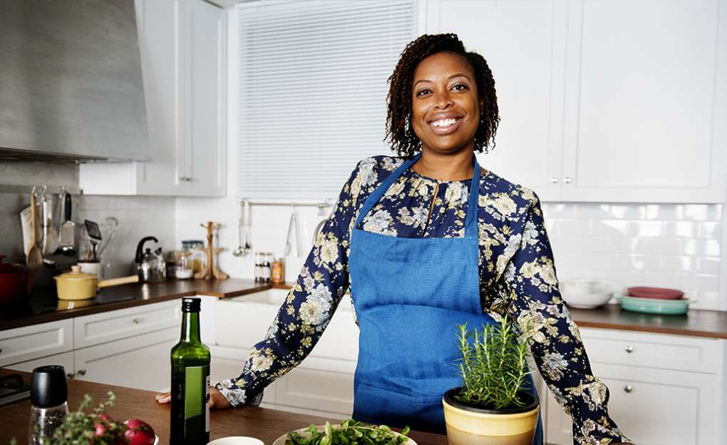 A young woman happily cooks in her home kitchen.