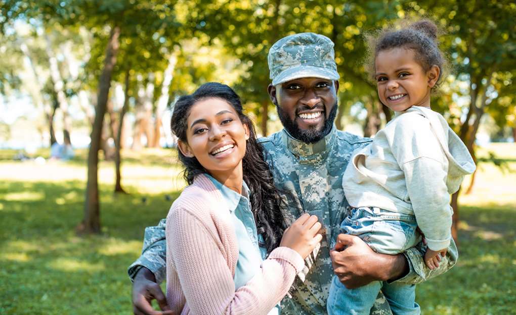 A uniformed soldier embracing his family