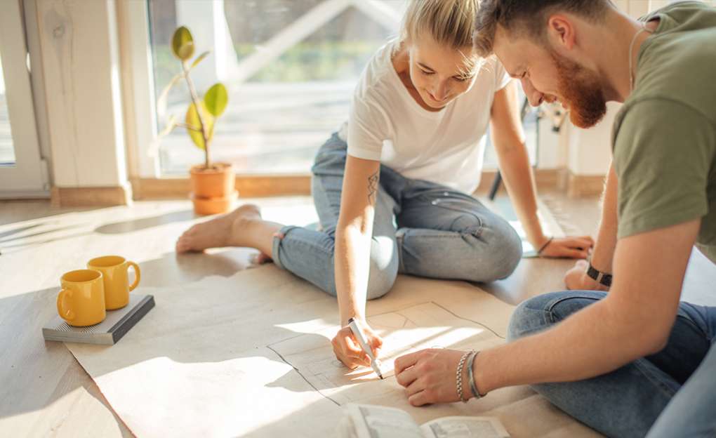 A young couple sitting on the floor drawing on a large piece of paper