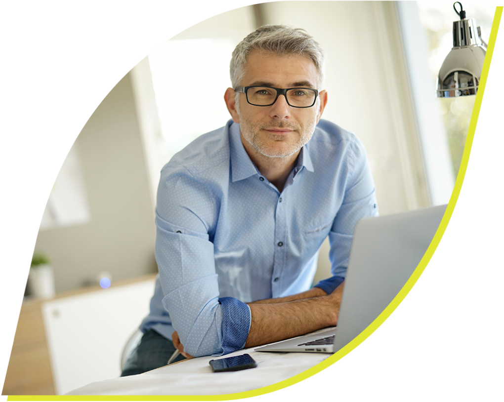 A middle aged businessman sits in front of a laptop.