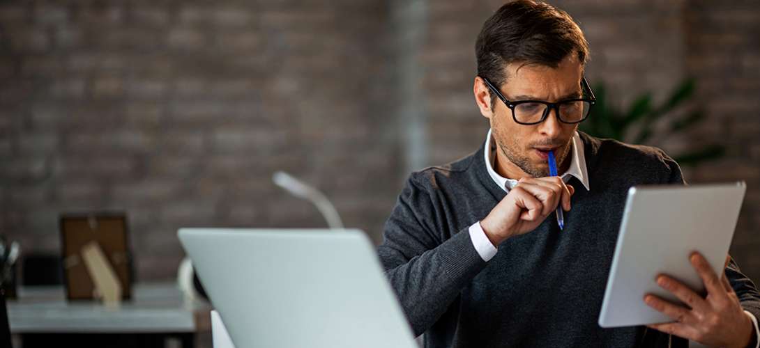 A well dressed man sitting in front of a laptop seems deep in thought.