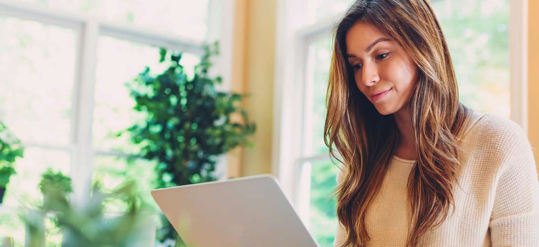 A young woman reviews checking accounts on her laptop.