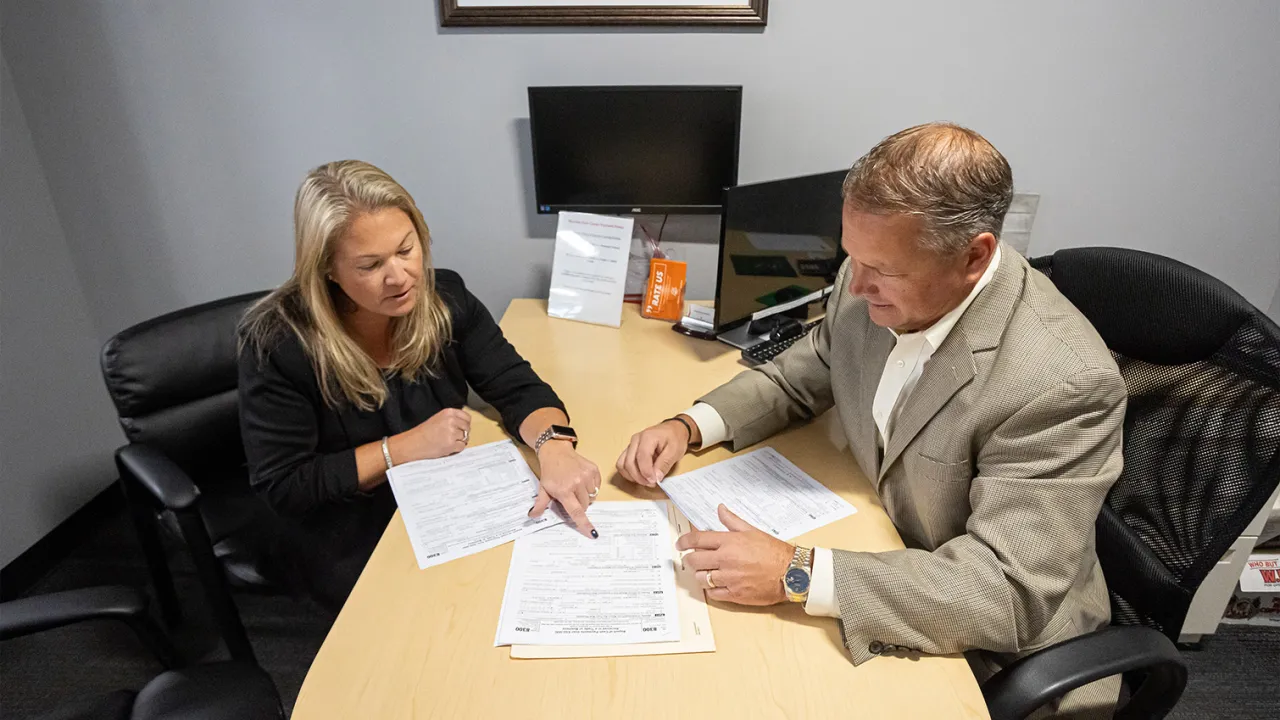 A North Easton Savings Bank lender and customer sitting across from each other at a desk and looking over paperwork together