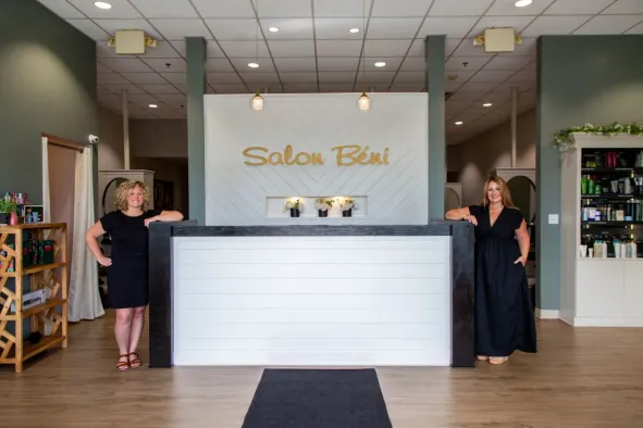 Two North Easton Savings Bank local business partners smiling and leaning against a counter inside a salon