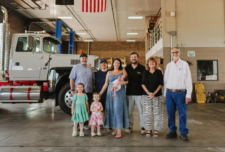 The Lucini family standing in their garage with trucks in the background